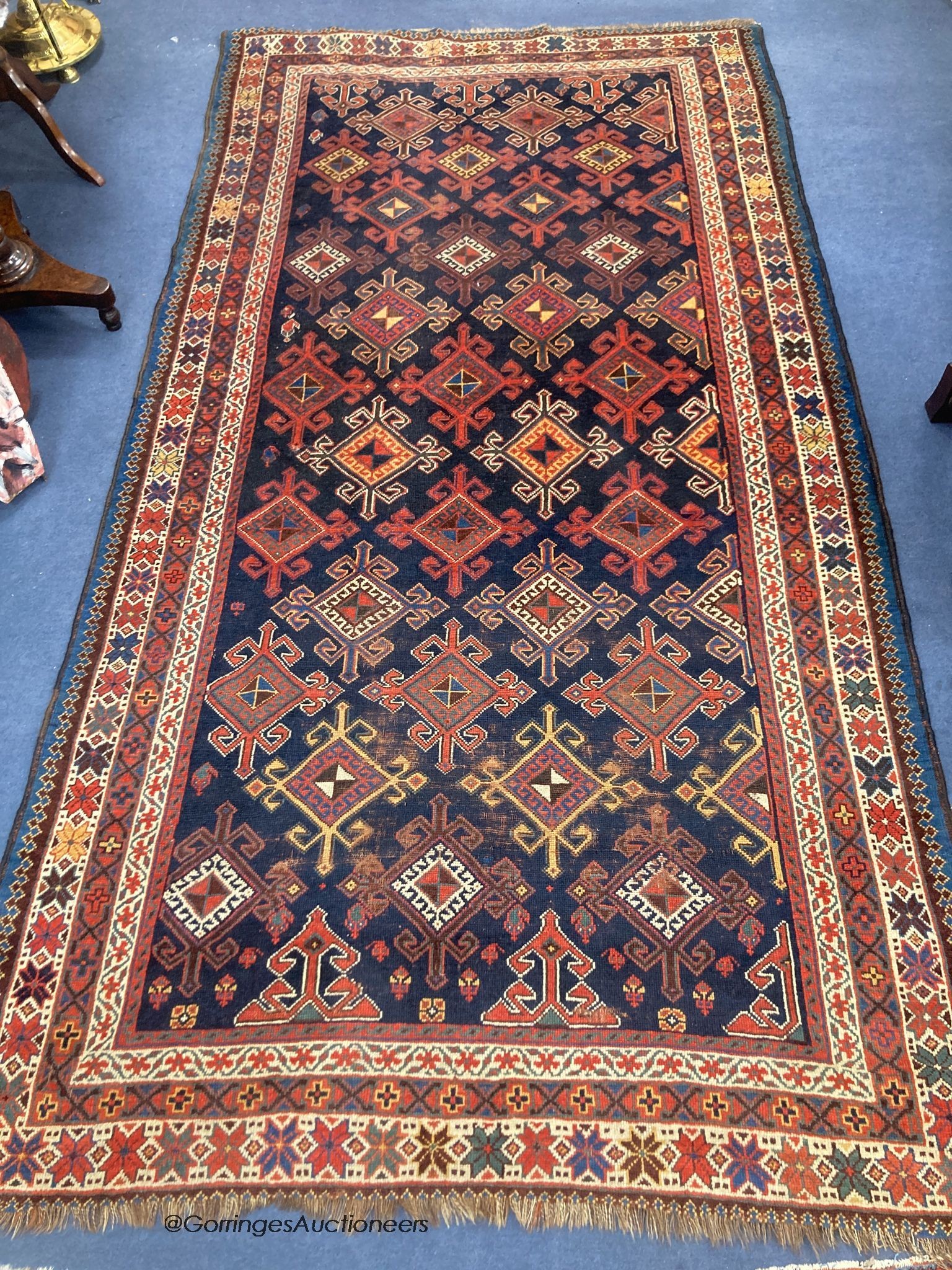 A Caucasian blue ground rug, woven with hooked lozenges, 288 x 152cm